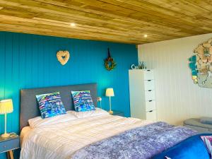 阿博伦The Pod & Cwtch luxury accommodation的一间卧室设有一张床和蓝色的墙壁