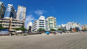 伊塔佩马Apartamento pé na areia em Itapema.的沙滩上,有建筑,有人坐在沙滩上
