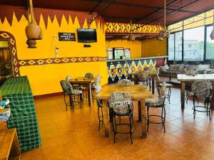 阿鲁沙Arusha Backpackers Hotel的餐厅设有桌椅和黄色的墙壁