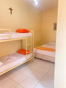 卡舒埃拉保利斯塔Pousada Lirio do Vale的小房间设有两张双层床和十字架