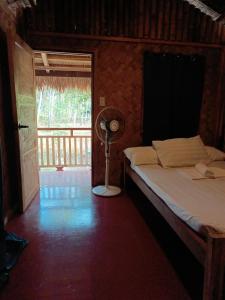 爱妮岛Zhaya's Beach & Cottages的一间卧室配有一张带风扇和窗户的床。