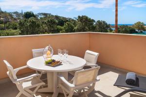 金塔湖Extraordinary Villa on an elevated position in Quinta do Lago的阳台上配有带椅子和酒杯的白色桌子
