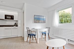洛桑Sallaz Residence by Homenhancement的白色的厨房配有白色的桌子和椅子