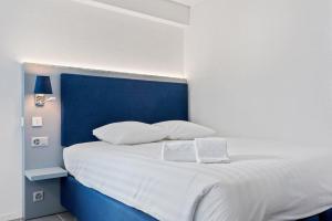 洛桑Sallaz Residence by Homenhancement的白色的床,配有蓝色床头板和白色枕头