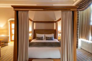 邓凯尔德邓凯尔德之家酒店的卧室配有带白色床单和枕头的天蓬床。