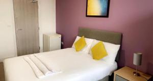 韦克菲尔德Sandal Park View - Duplex Relocations的一间卧室配有白色床和黄色枕头