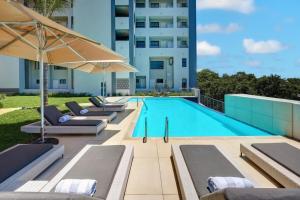 比勒陀利亚Entire luxury 2 bedroom en-suite apartment at Regency Hotel的一个带躺椅和遮阳伞的游泳池