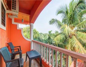 巴加Hotel Adam's Baga Beach Resort Goa - 2 minutes walk from Baga Beach的阳台配有两把椅子和棕榈树