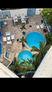 福塔莱萨Villa Del Sol Hotel Fortaleza的享有两个游泳池的顶部景致,泳池配有椅子和棕榈树
