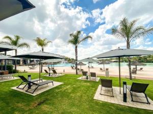 比勒陀利亚Luxury beach lagoon 1 Bedroom apartment的一个带椅子和遮阳伞的公园和一个海滩