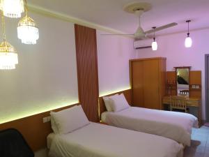 FuvahmulahFuvahmulah inn的酒店客房配有两张床和吊扇。