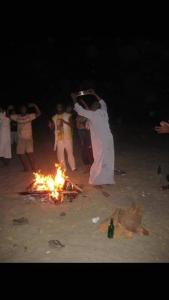 阿斯旺Felucca Sailing Boat Overnight Experience的一群人在海滩上的火堆旁跳舞
