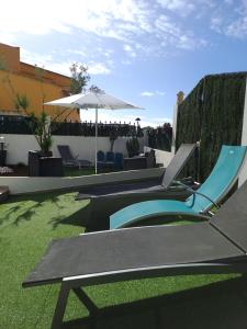 奥良Lovely new House - Guests Apartments的庭院设有椅子、遮阳伞和草地。