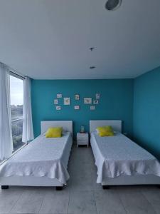 普拉亚科罗纳多Apartamento de playa con vista al mar en coronado的蓝色墙壁客房的两张床