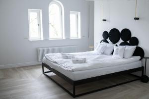 罗兹Srebrna Luxury Apartments - willa fabrykancka的白色卧室配有一张大床和黑色床头板