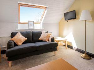 FarlamAlder Cottage - Uk46154的客厅配有黑色沙发和窗户