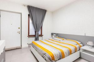 皮亚琴察Casa Maddalena的白色卧室配有黄色和白色条纹床