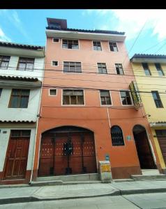 阿亚库乔HOSPEDAJE EL ARCO的一座橙色的建筑,设有两扇门和一个车库