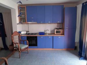 Baia das GatasVivenda Na Baia das Gatas的厨房配有蓝色橱柜、椅子和微波炉