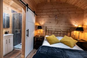 邓加文The Hen Harrier - 4 Person Luxury Glamping Cabin的一间卧室设有木墙和一张带黄色枕头的床。