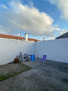 佩洛塔斯Casa em Condomínio Fechado的两把椅子和一辆自行车停在白色墙壁旁边
