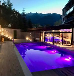 班斯科6 Luxury SPA Apartments TOP resort Bansko - incl wellness的游泳池在晚上点亮,紫色灯