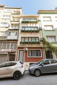 伊斯坦布尔Kiztasi Apartments-Orange and Blue的两辆汽车停在大楼前