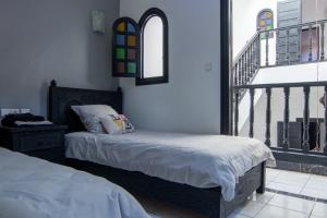 马拉喀什RIAD TAWSALANE的一间带两张床的卧室和一个阳台