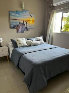 Baie NettleThe little Heaven的一间卧室配有一张带蓝色毯子的床和窗户。