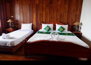 Muang Không肯格马尼克洛尼亚尔旅馆的卧室配有一张床上的2个白色天鹅
