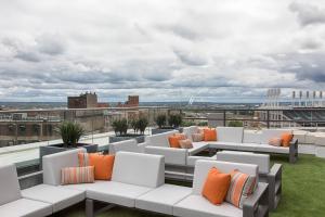 克利夫兰第9街大都会品牌系列酒店的屋顶露台配有白色沙发和橙色枕头。