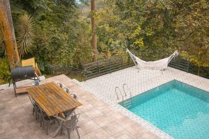 茂物Villa Jenis By The Villas 100的一个带木桌和一张桌子旁吊床的游泳池
