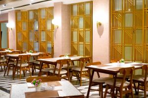 班达亚齐Portola Arabia Hotel Banda Aceh的餐厅设有木桌、椅子和窗户。