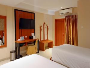 班达亚齐Portola Arabia Hotel Banda Aceh的一间卧室配有一张床和一张书桌及电视