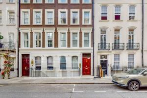 伦敦Park Lane Apartments Mayfair Collection的停在大楼前的红色门的汽车