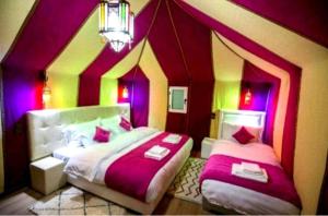 梅尔祖卡Merzouga Luxurious Camp的一间卧室设有两张紫色和黄色墙壁的床。