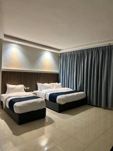 亚喀巴Aladnan hotel的配有窗帘的酒店客房内的两张床