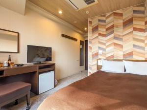 宇部宇部市新盖亚酒店的一间卧室配有一张床、一张书桌和一台电视