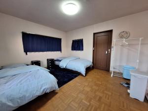 Mimaseguesthouse ONAKA的一间卧室设有两张床,铺有木地板