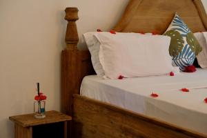 吉汶瓦巴哈蒂酒店的一张铺有白色床单和红色鲜花的床