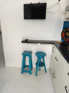 塞博河畔卡莱塔Loft la Caletilla的厨房配有2张蓝色凳子,墙上配有电视
