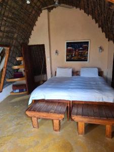 姆巴巴内Hawane Resort的一间卧室配有一张带两张木制长椅的床