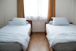 安汶Wisma Grace的带窗户的客房内设有两张单人床。