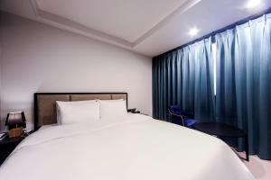 釜山ON:NA Hotel的卧室配有白色的床和蓝色窗帘