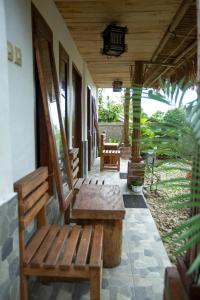 普拉亚Tastura Homestay的门廊,房子上设有两个木长椅