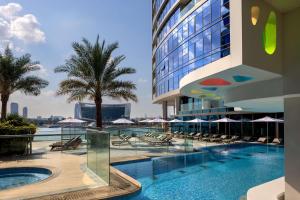 迪拜Hilton Dubai Creek Hotel & Residences的酒店游泳池设有椅子和遮阳伞
