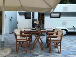 斯卡拉福卡斯Delightful RV Camper In a Peaceful Area near Sea.的一张带雨伞和面包车的木桌和椅子
