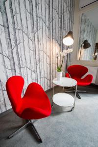 罗兹维哥酒店的一间设有两张红色椅子和一张桌子的房间