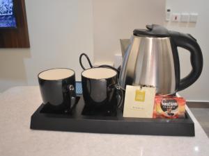 Rabbaكيان للأجنحة الفندقية- احد رفيده的咖啡壶和柜台上的两个杯子