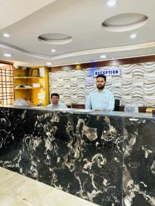 班加罗尔Hotel Chetan International的两个男人站在餐厅柜台后面